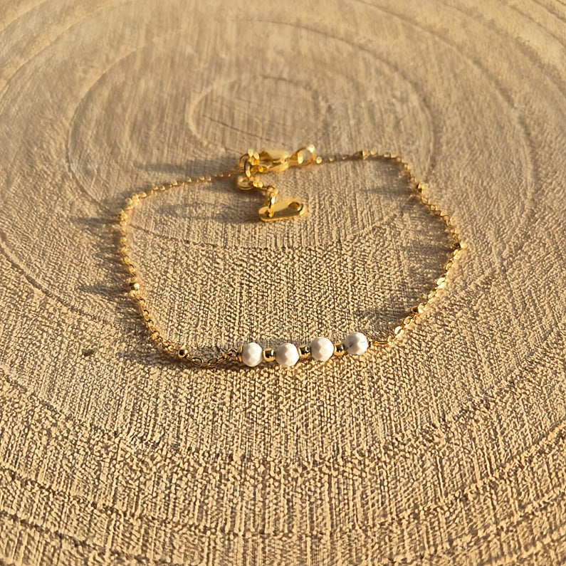 Bracelet fin en Howlite naturelle 2 à 3 mm avec quatre perles, monté sur chaîne dorée en acier inoxydable, création artisanale Les Secrets de G&M.