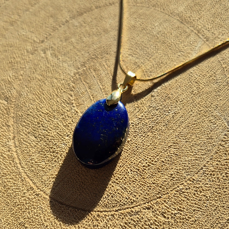 Collier avec pendentif en lapis lazuli bleu profond sur chaîne dorée.