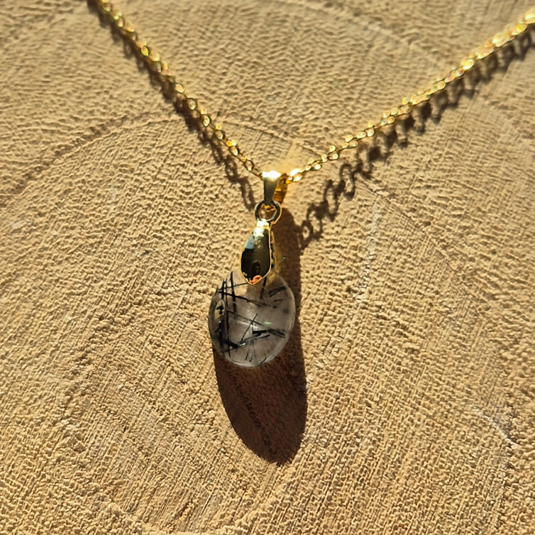 Collier chaine dorée avec pendentif goutte en quartz tourmaliné transparent avec inclusions noires.