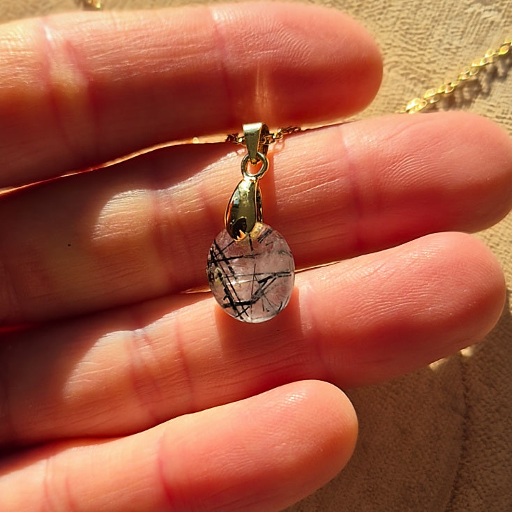 Collier chaine dorée avec pendentif goutte en quartz tourmaliné transparent avec inclusions noires.
