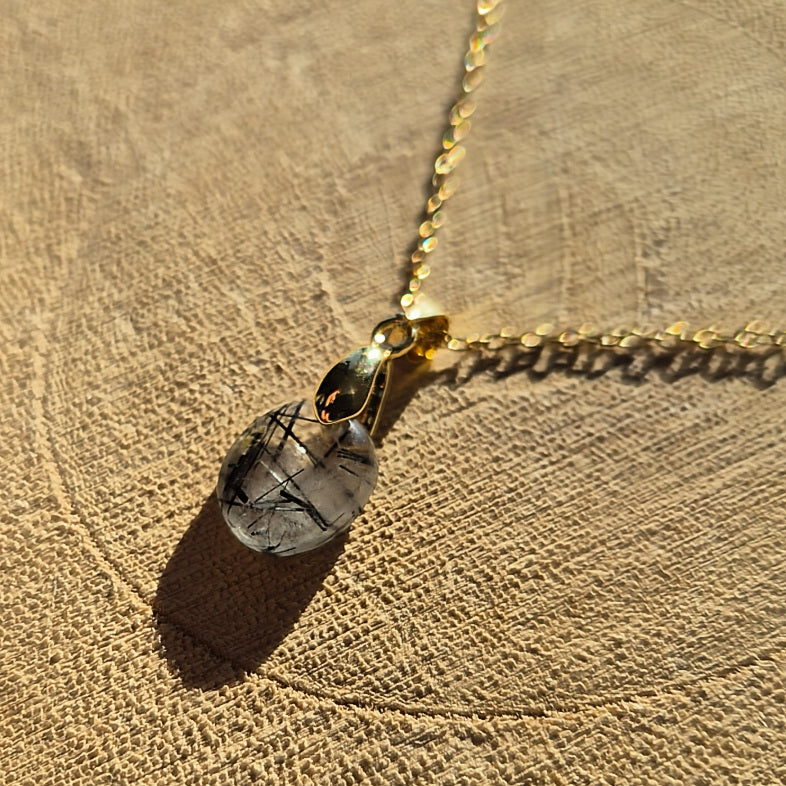Collier chaine dorée avec pendentif goutte en quartz tourmaliné transparent avec inclusions noires.