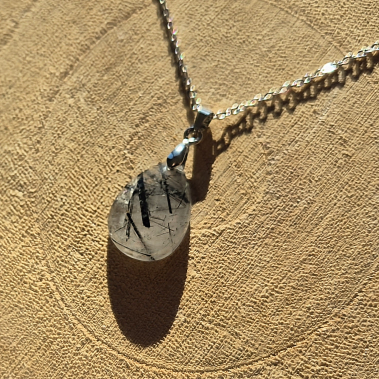 Collier avec pendentif goutte en quartz tourmaliné transparent avec inclusions noires.