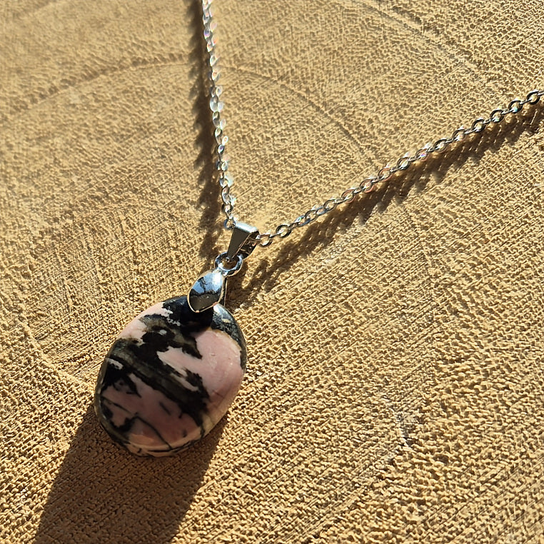 Collier avec pendentif en rhodonite rose et noir d’environ 2 cm sur chaîne.