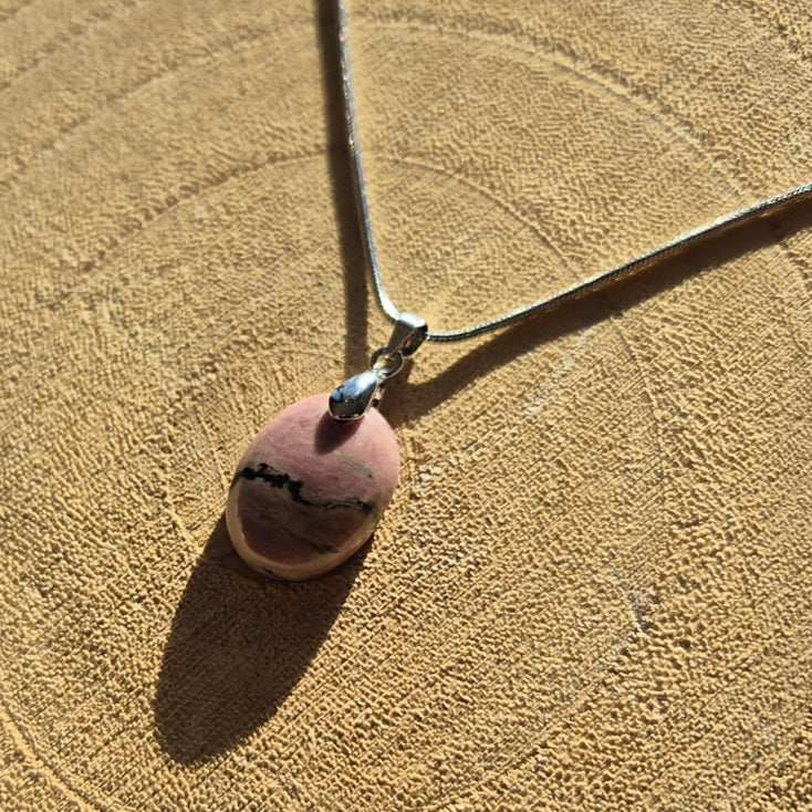 Collier avec pendentif en rhodonite rose et noir d’environ 2 cm sur chaîne.