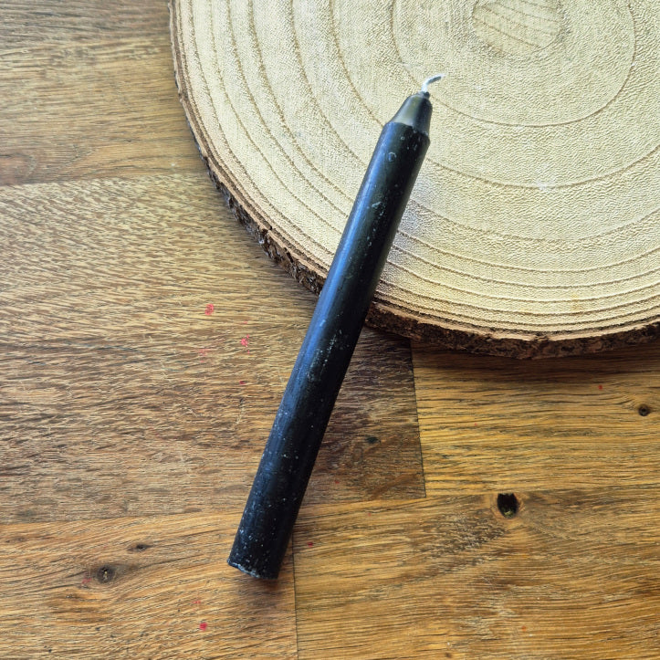 Bougie noire de rituel allumée, symbole de protection, de libération et de transformation. Utilisée pour dissoudre les énergies négatives et accompagner les travaux de purification.