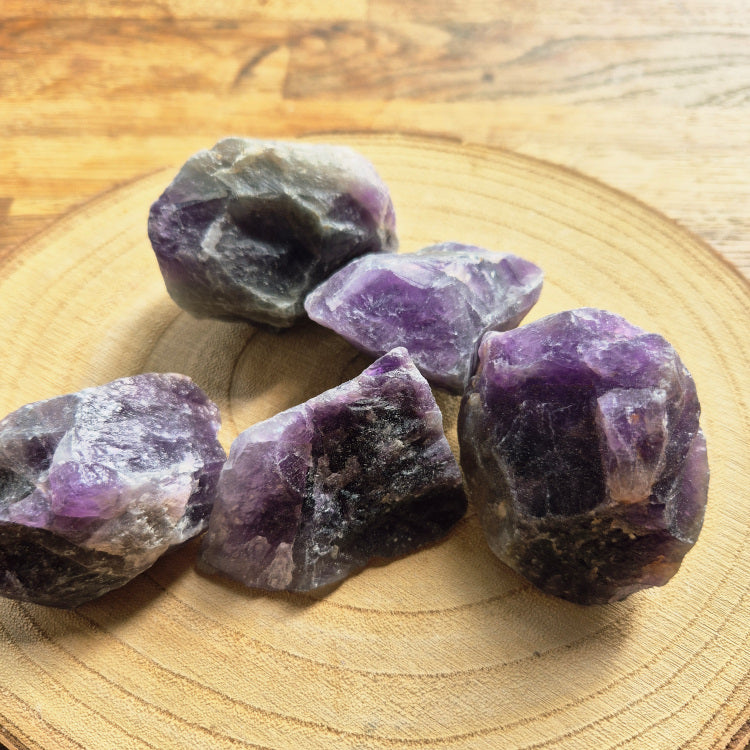 Pierre brute d’améthyste violette (~6 cm), cristaux naturels non polis, teintes lavande à pourpre, posée sur fond blanc, symbole sérénité et protection.