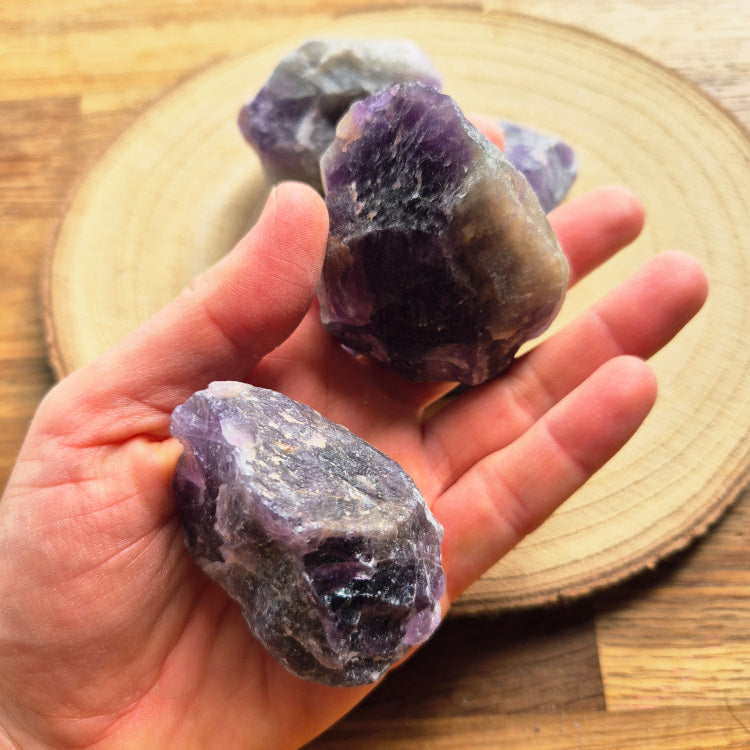 Pierre brute d’améthyste violette (~6 cm), cristaux naturels non polis, teintes lavande à pourpre, posée sur fond blanc, symbole sérénité et protection.