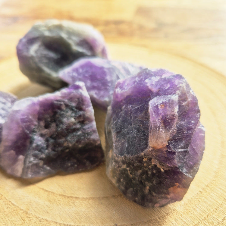 Pierre brute d’améthyste violette (~6 cm), cristaux naturels non polis, teintes lavande à pourpre, posée sur fond blanc, symbole sérénité et protection.